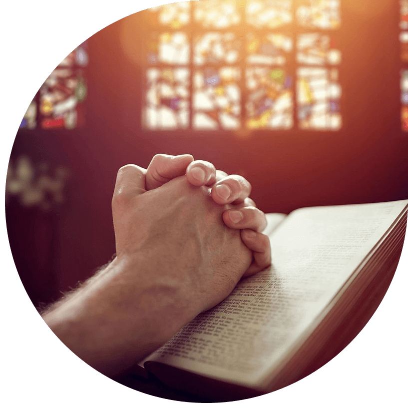 A person is praying on the bible in front of a window.