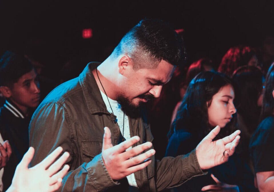 A man is praying in front of other people.